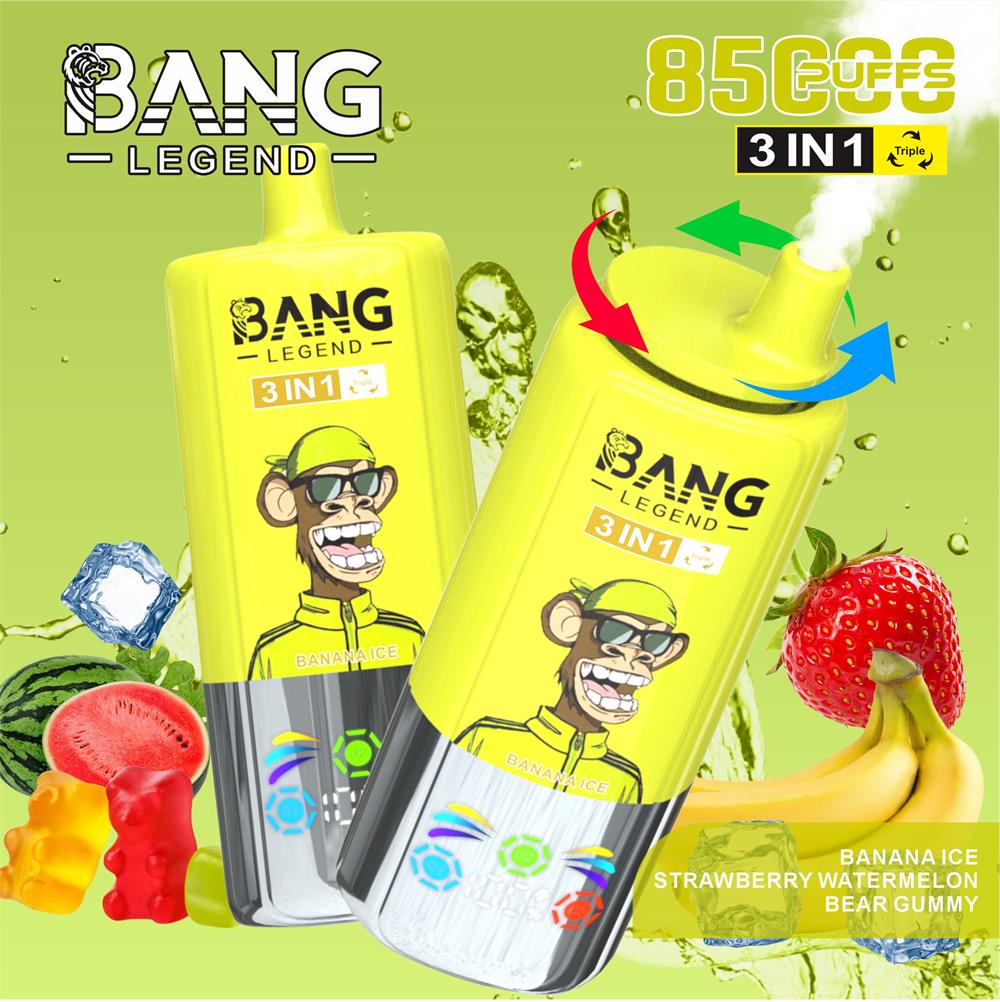 Two bright yellow disposable vape devices branded BANG LEGEND with a 3-in-1 label and a cartoon monkey character, one emitting a puff of vapour, surrounded by strawberries, bananas, watermelon slices, gummy bears and ice cubes on a green background, with prominent puff-count text and coloured arrows indicating airflow.