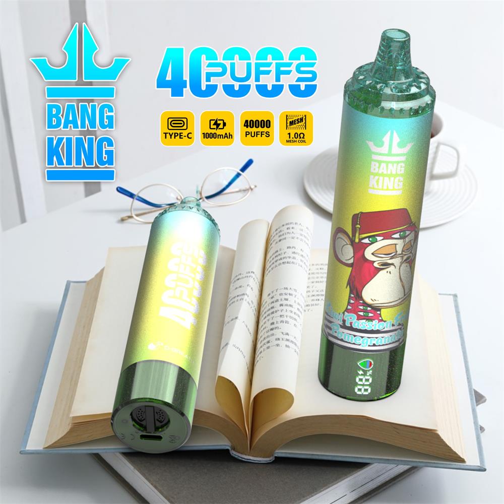 Two iridescent green disposable vapes branded "Bang King"—one standing upright with a cartoon monkey label and digital puff counter, the other lying on its side—rest on an open book with reading glasses and a plate in the background, with prominent "40,000 puffs" and charging/icons graphics.