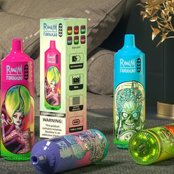 Three brightly coloured RandM Tornado disposable vape devices with bold cartoon artwork — pink, blue and multi‑coloured — arranged around the product box displaying feature icons and a nicotine warning, placed on a table in a living‑room setting with grey cushions and a decorative gold plant.