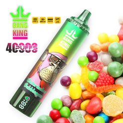 Green metallic disposable vape device labelled BANG KING with a cartoon monkey and 'Watermelon Bubblegum' flavour text, pictured beside a colourful pile of gummy and hard candies and a 40,000-puffs promotional badge
