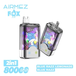 Packaging image showing two transparent rectangular Airmez Fox vape devices with silver bases and clear mouthpieces, each displaying a colourful blue fox illustration with paint-splash accents, plus the Airmez Fox logo at top left and text indicating 2-in-1, 800 puffs and flavours ‘Blue Razz Lemonade’ and ‘Blue Razz’.